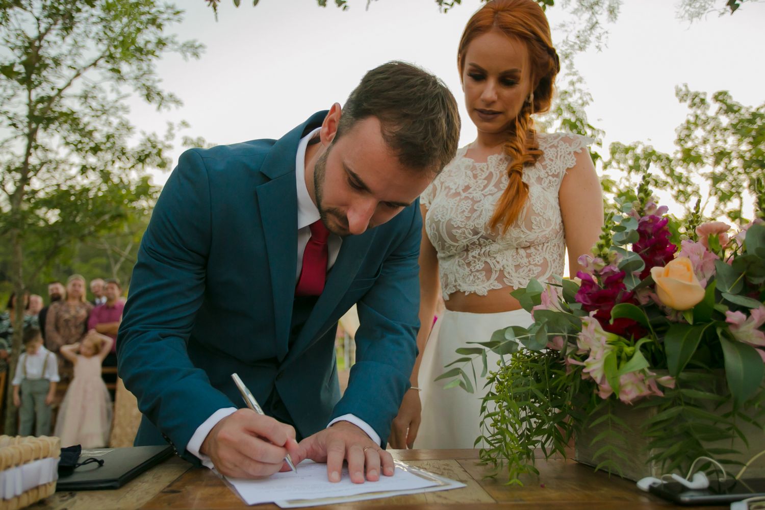 Signing of the wedding documents during an outdoor ceremony with floral decorations.