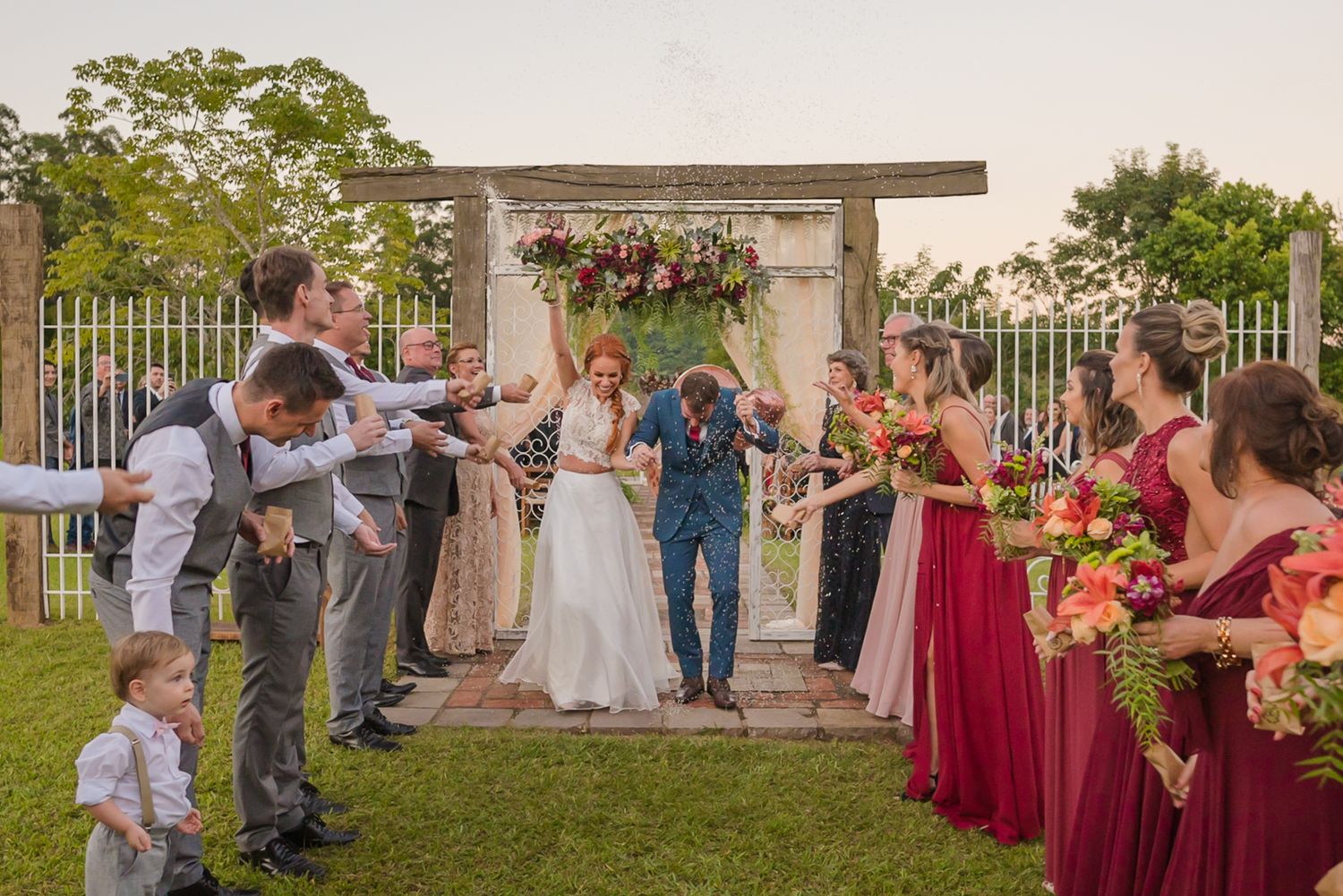 Wedding party lines outdoor ceremony space with flowers and decorative arch.