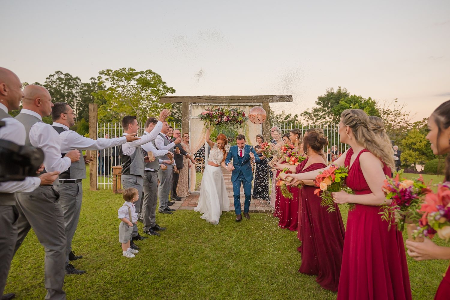 Wedding party celebrates with confetti toss at outdoor ceremony space.