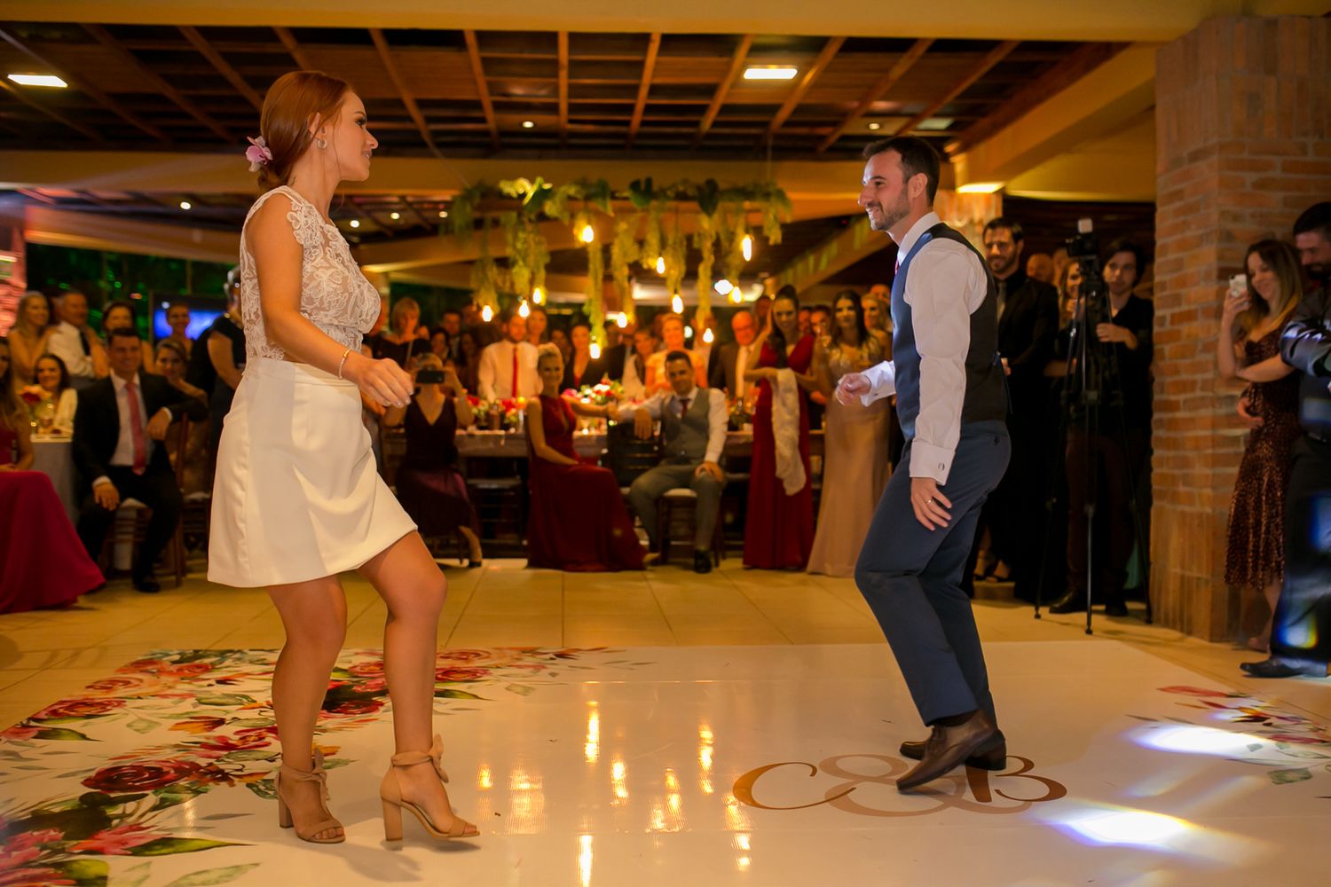 Couple dancing energetically on an illuminated dance floor during their wedding reception.