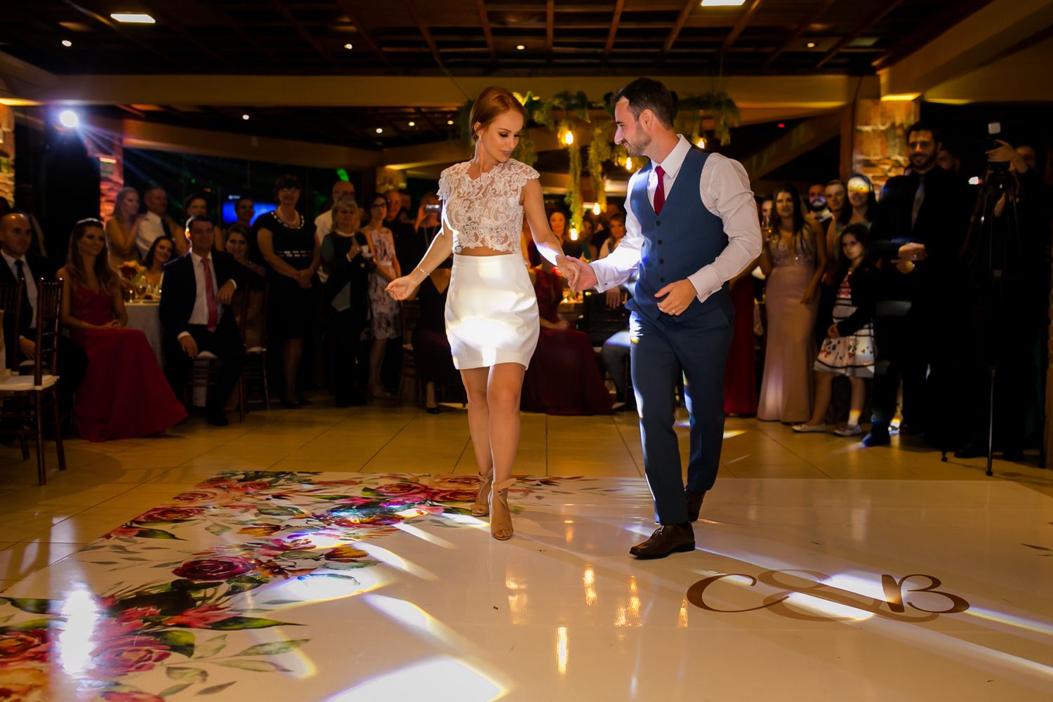 A couple performs a choreographed dance routine on a decorated wedding reception dance floor.