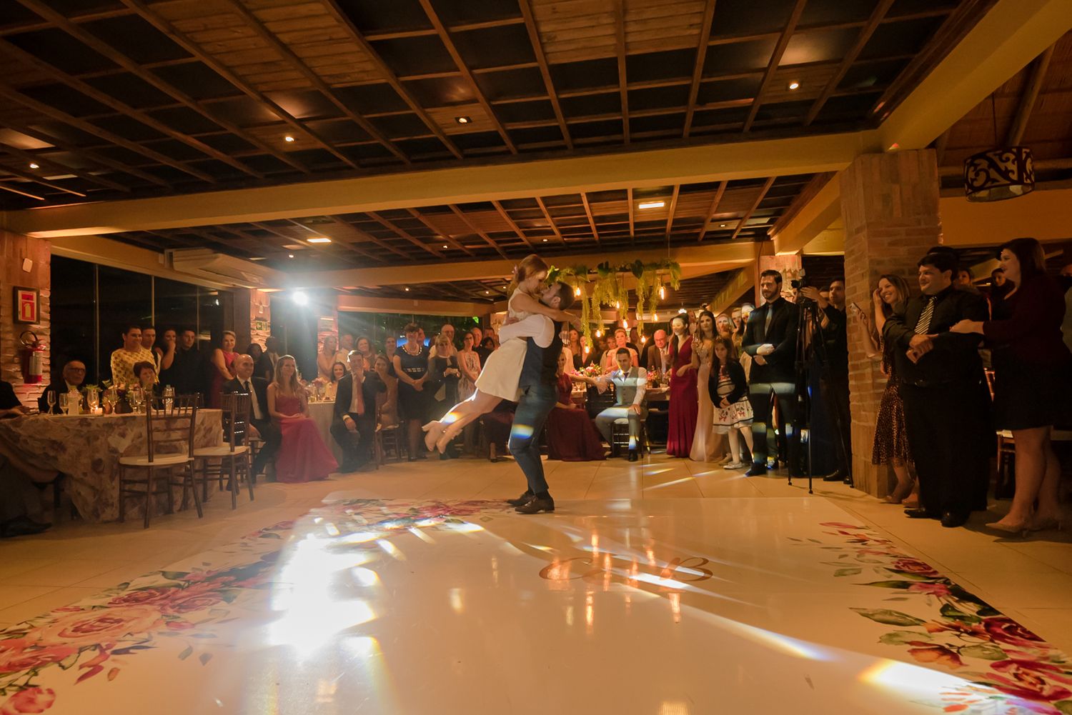 Wedding guests surround an illuminated dance floor as a couple performs a special dance number.