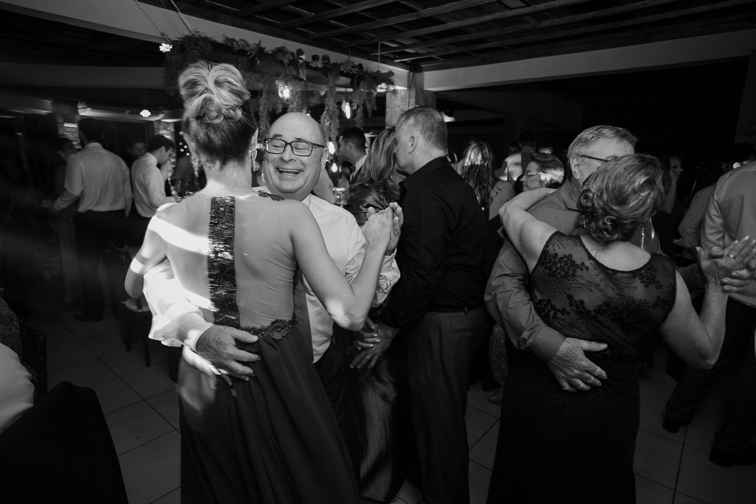 Black and white photo of wedding guests dancing enthusiastically at the reception.