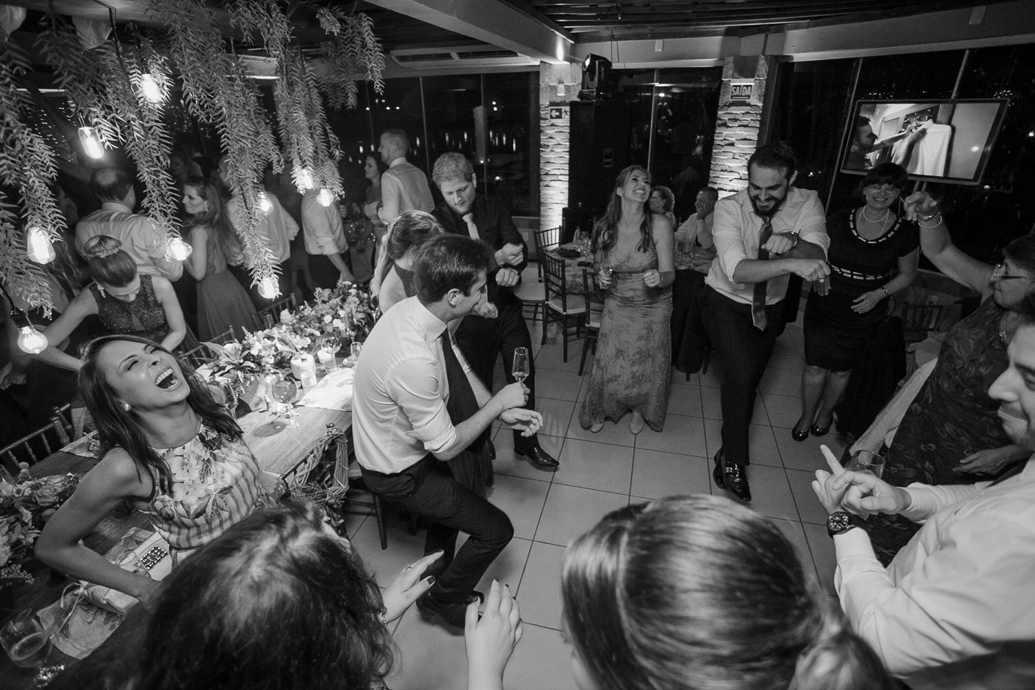 Wedding guests gather in a circle on the dance floor during a reception celebration.