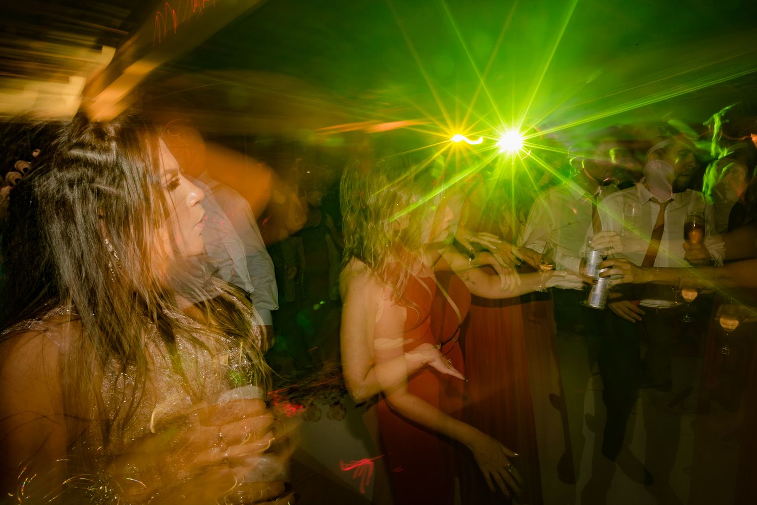 Dance floor illuminated by bright green lights with motion-blurred dancers creating an energetic atmosphere.