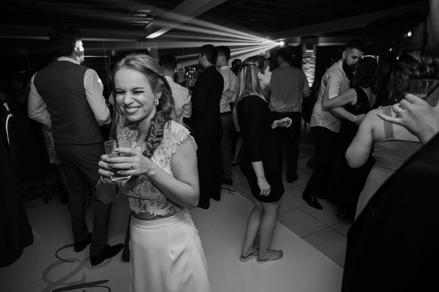 Black and white photo of a guest enjoying drinks and dancing at a reception celebration.