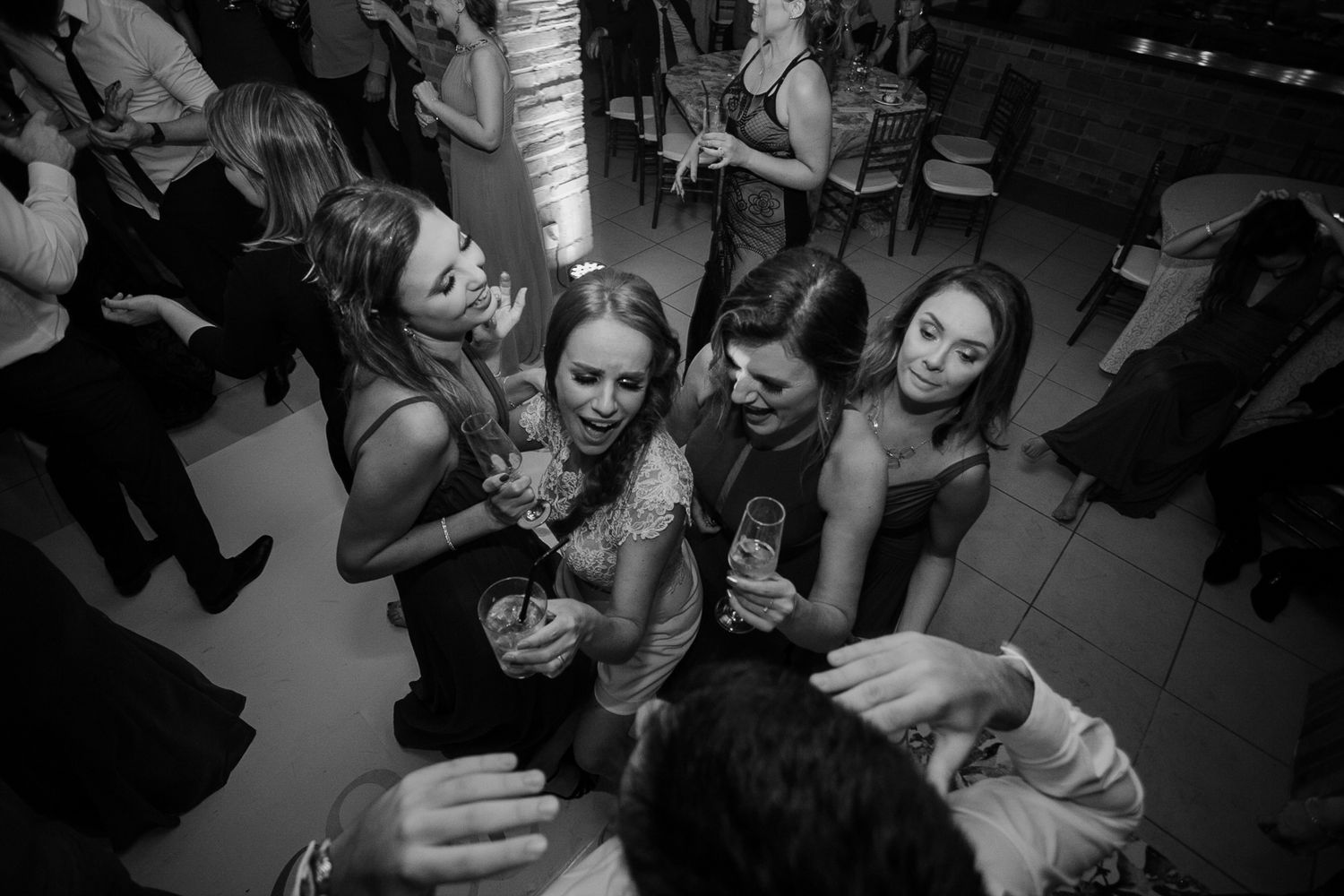 Party guests gather closely together for drinks and laughter at a dimly lit event.