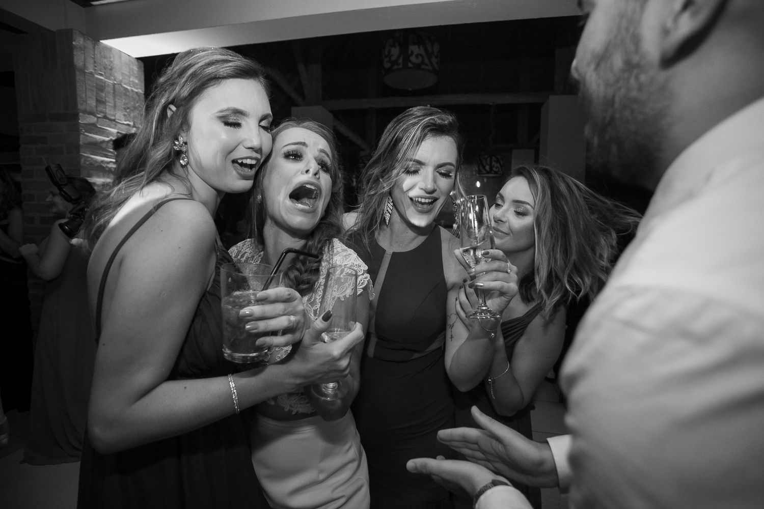 Group of friends share excited reactions while enjoying drinks at a party.