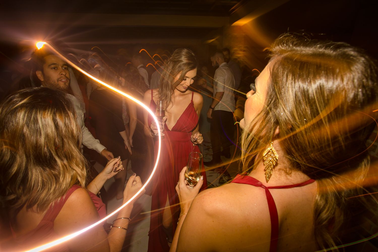 Colorful light trails illuminate dancers at a nighttime party.