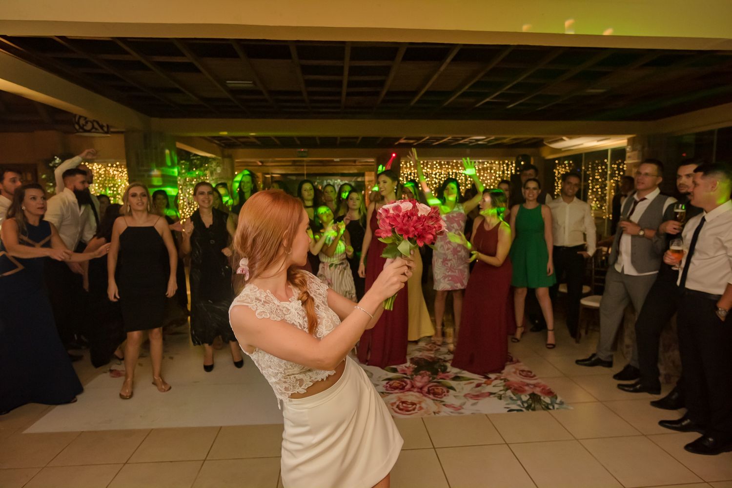A bride prepares to toss her bouquet to waiting wedding guests.