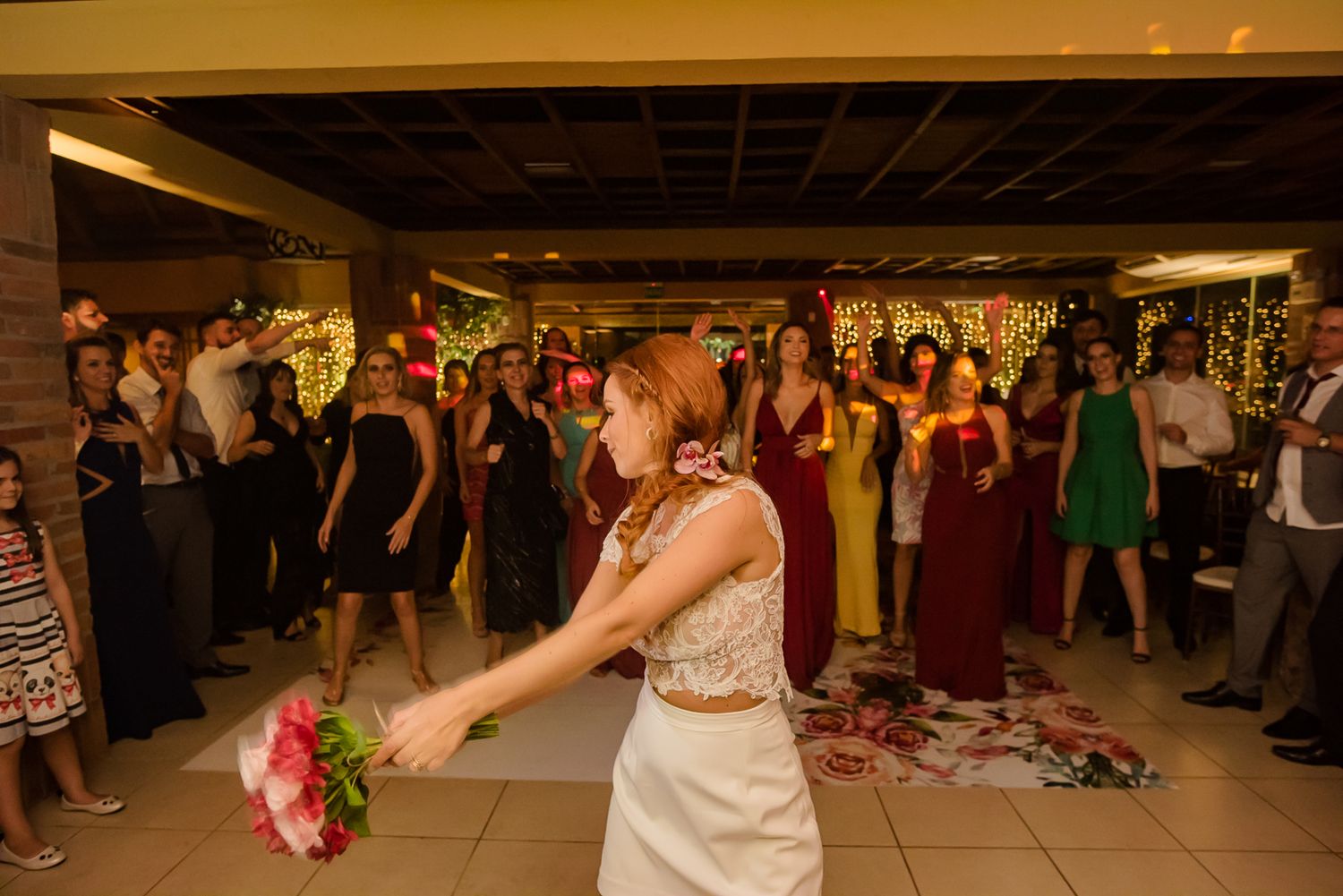 Bride getting ready to throw her bouquet at wedding reception with guests watching.