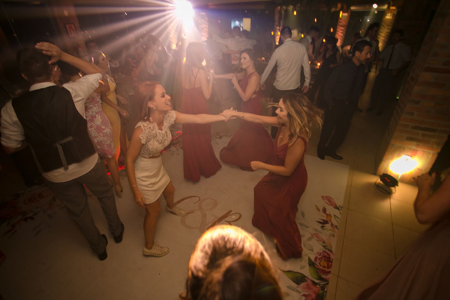 Guests dancing under dramatic lighting at an indoor wedding celebration.