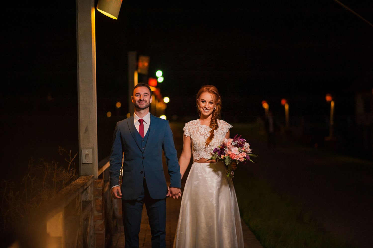 An evening portrait on a path with glowing lanterns in the background.