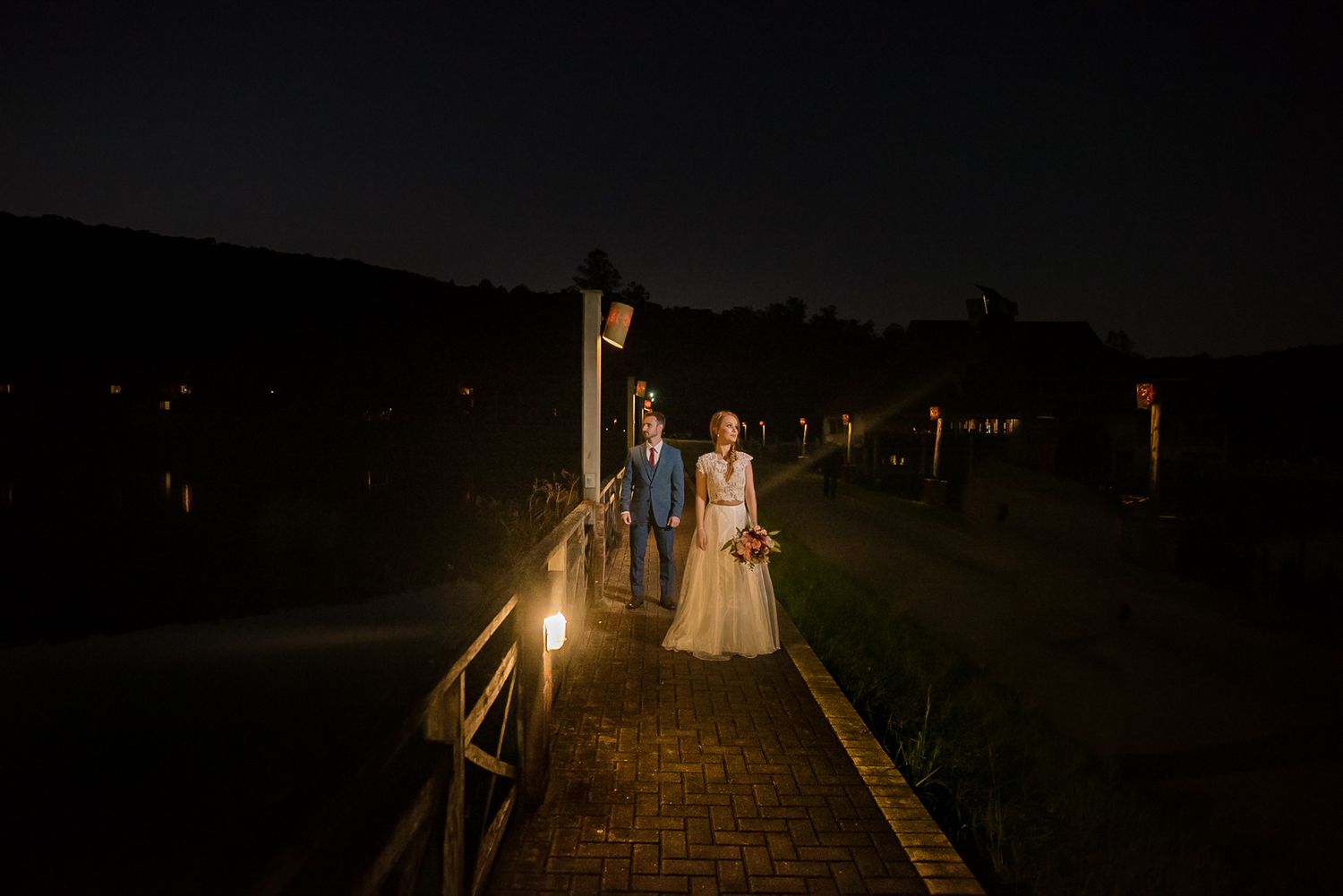 A romantic nighttime scene on a wooden boardwalk lit by soft ambient lights.