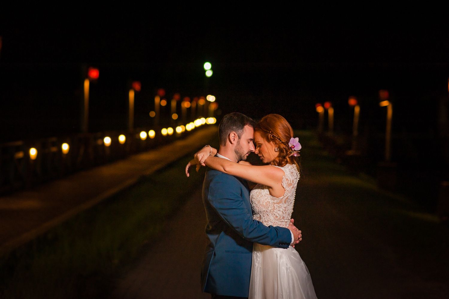 A romantic embrace on a path lined with glowing lights at night.