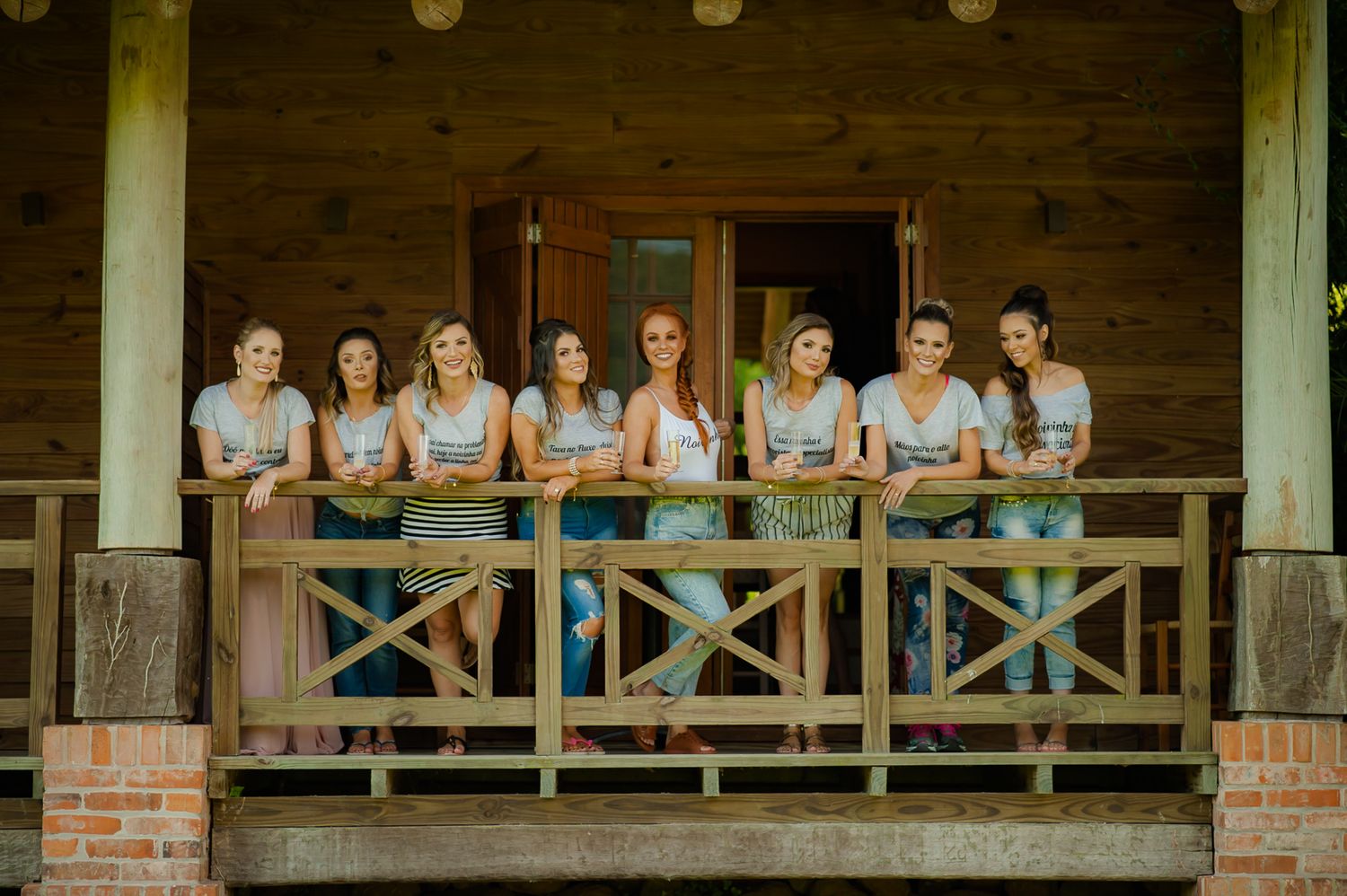 A group poses together on a wooden porch wearing matching light blue dresses.