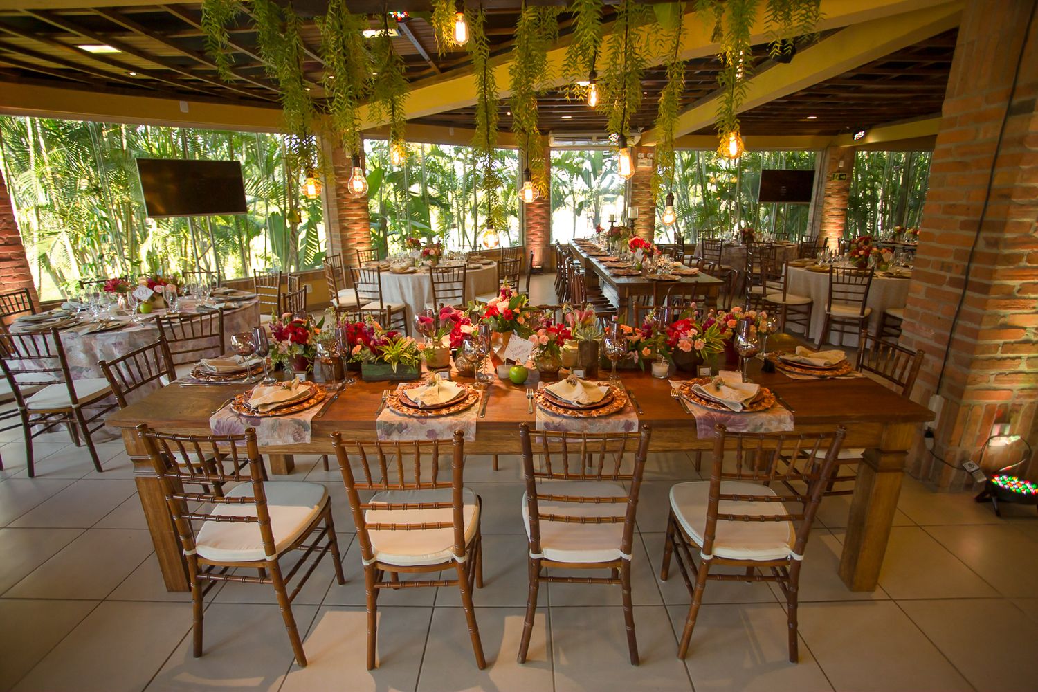 A rustic wedding reception venue with wooden chairs and floral table settings in natural lighting.