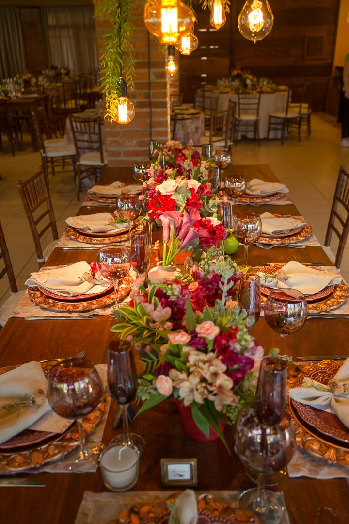 An elegant wedding reception table features vibrant floral centerpieces and vintage-style lighting.