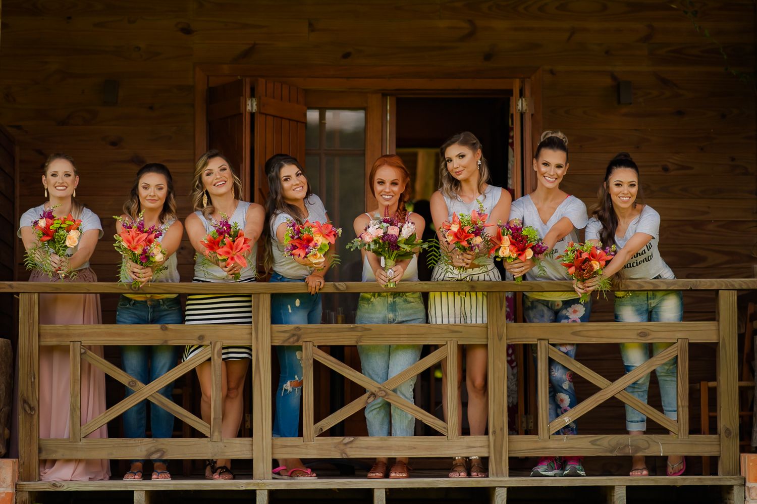 Group standing on wooden deck holding colorful autumn bouquets against rustic backdrop.
