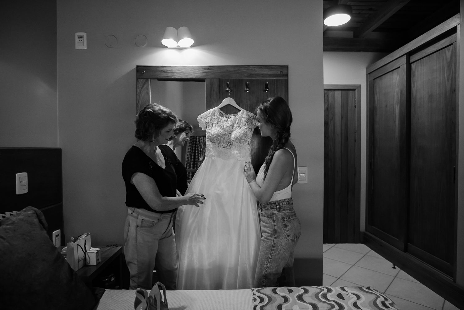 Wedding dress hanging in preparation room with soft lighting.