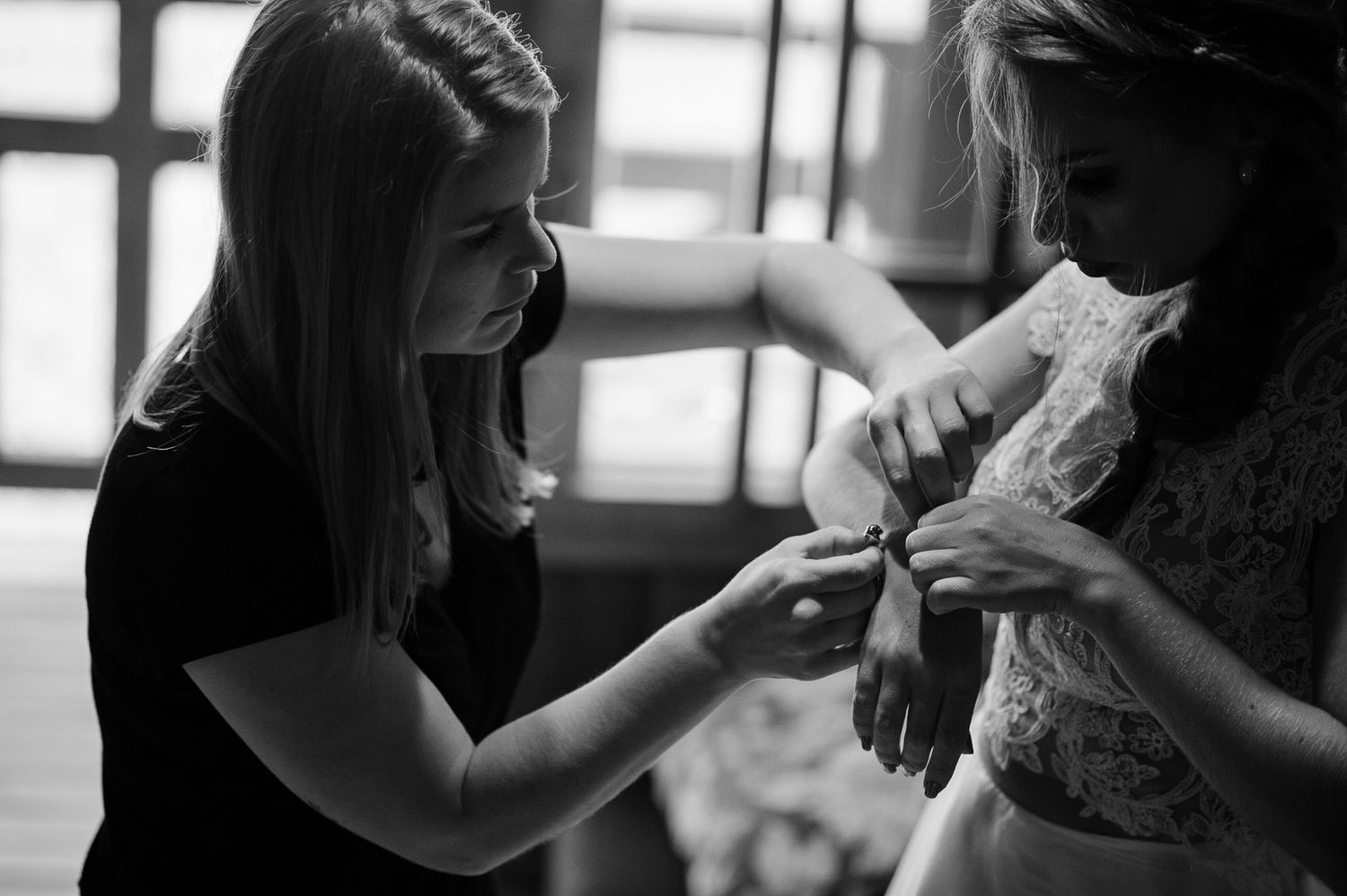 Black and white image showing final adjustments being made to a wedding dress.