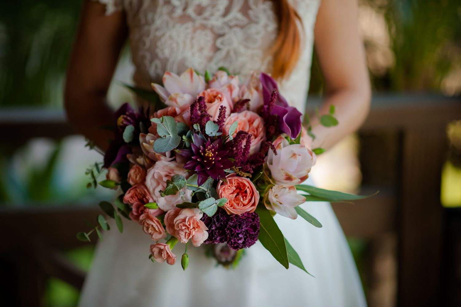 Close-up of a stunning bridal bouquet featuring pink, purple and peach roses with mixed greenery.