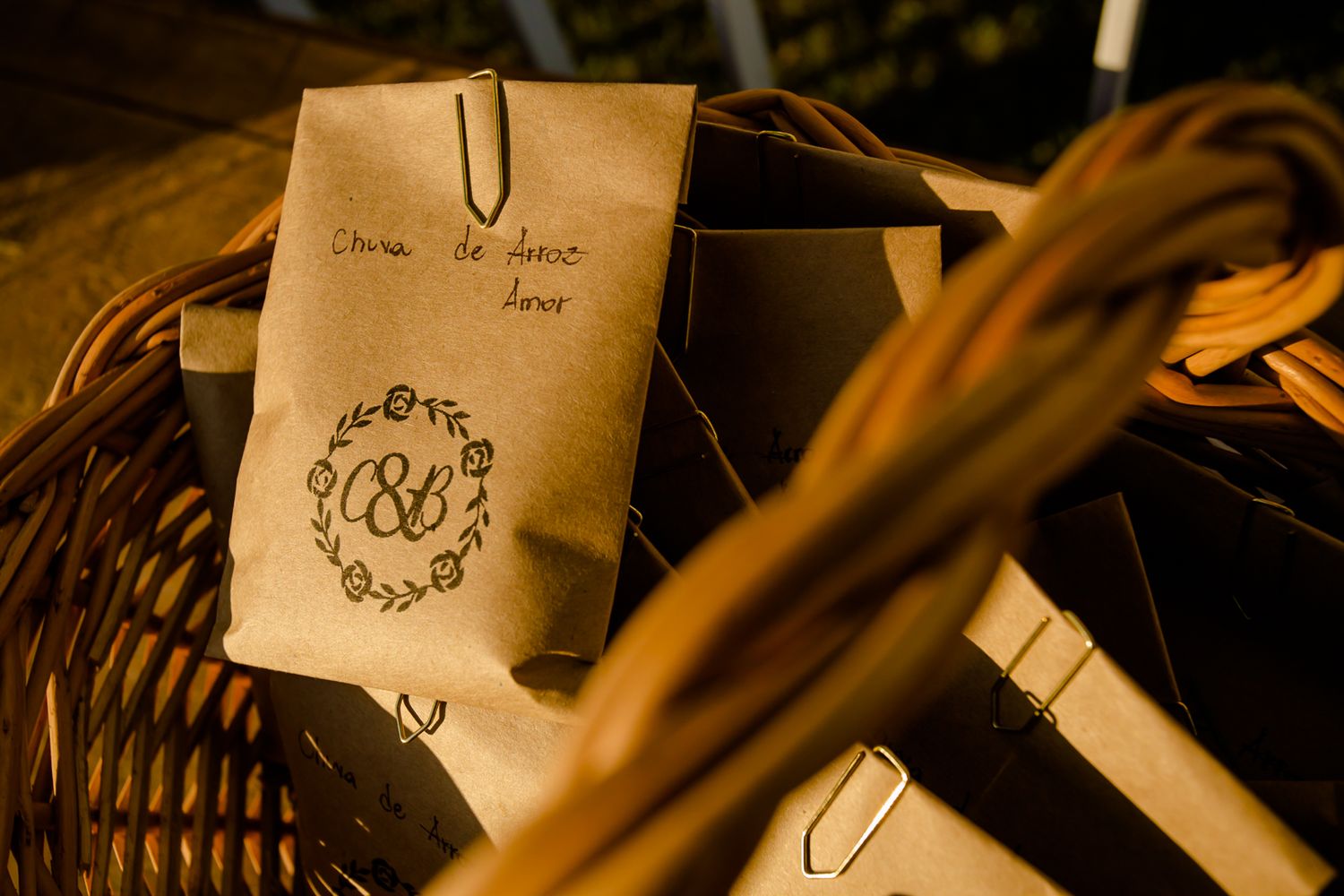 A vintage brown paper wedding favor bag with decorative monogram sitting in a woven basket.