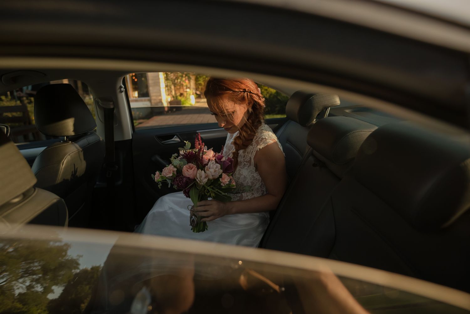 Interior car view of a bridal bouquet with romantic lighting through the window.