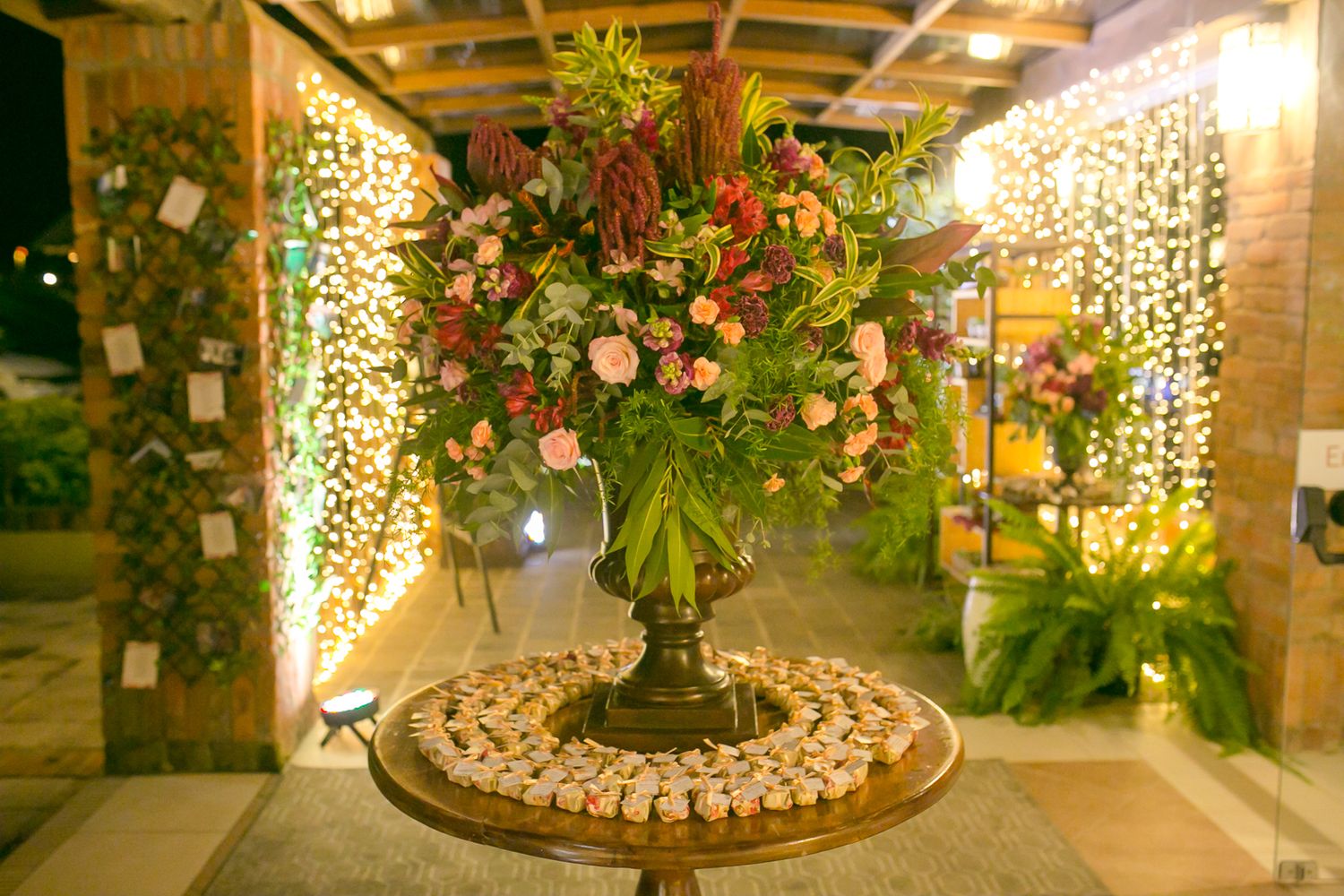 Elegant floral centerpiece arrangement with cascading lights and greenery at wedding reception.