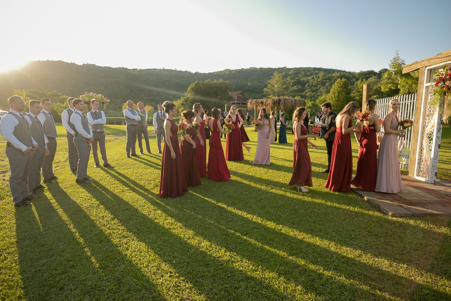 Wedding celebration on landscaped lawn with guests in formal attire at sunset.