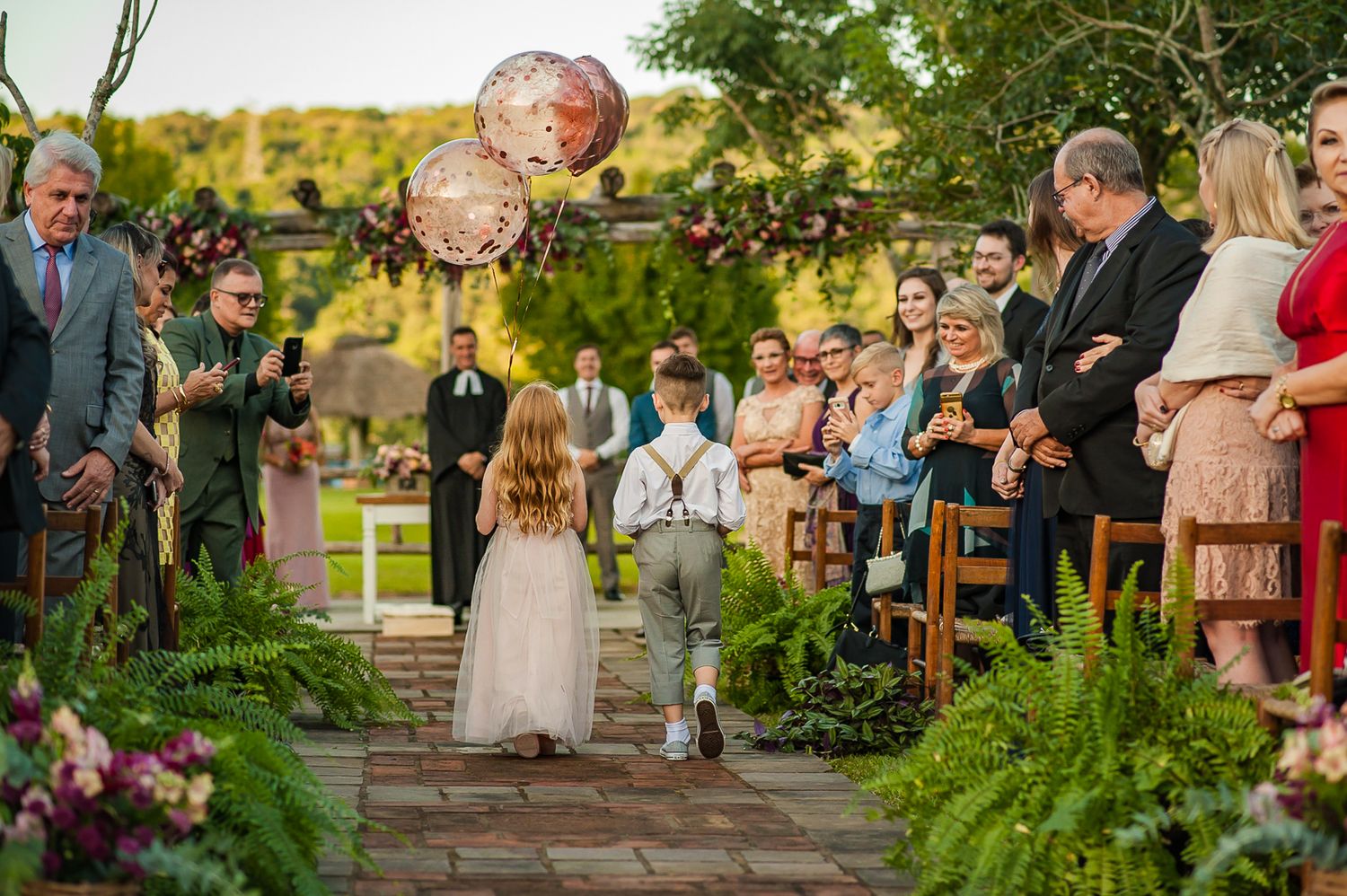Children walking down stone pathway during wedding ceremony with decorative balloons.