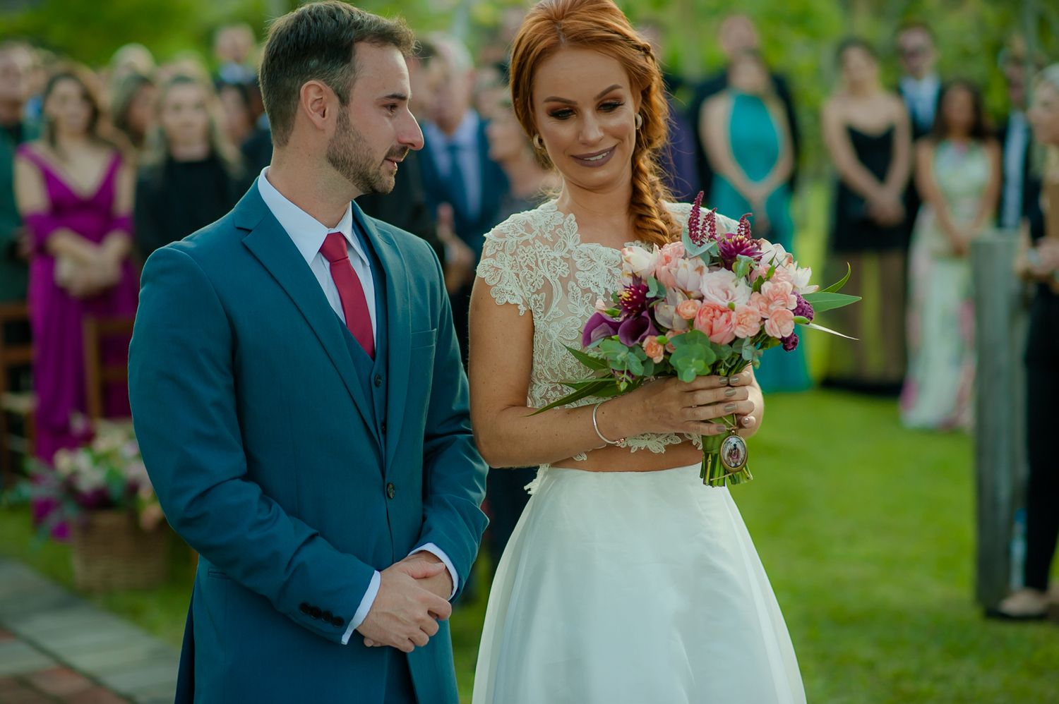 Intimate outdoor wedding ceremony moment with floral bouquet and garden setting.