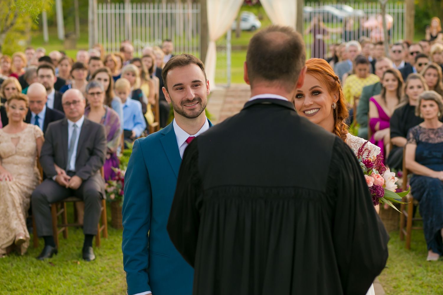 Outdoor wedding ceremony with large crowd of guests watching the proceedings.