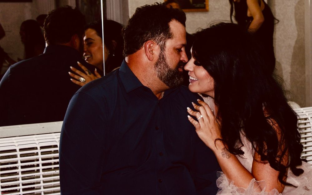 Romantic couple sharing an intimate moment, man in navy suit and woman with dark hair gazing at each other lovingly.