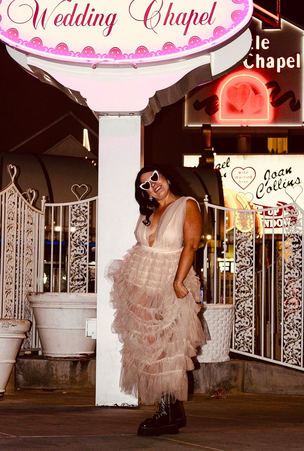 Woman in pink tulle dress posing outside a Las Vegas Wedding Chapel at night.