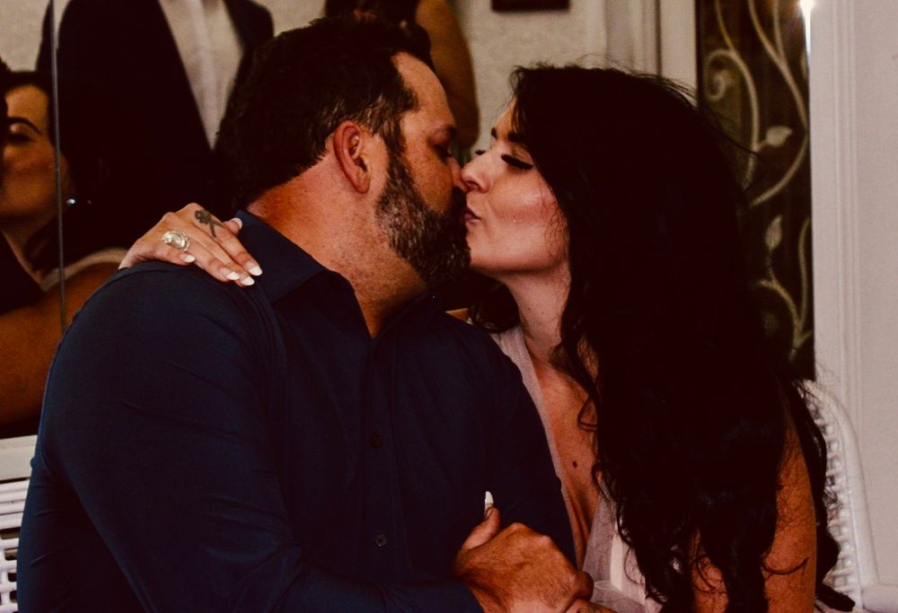 Couple sharing a romantic kiss at an indoor celebration or wedding reception event.
