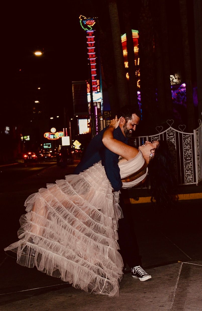 Couple dancing on Las Vegas street at night, man dipping woman in tulle dress.