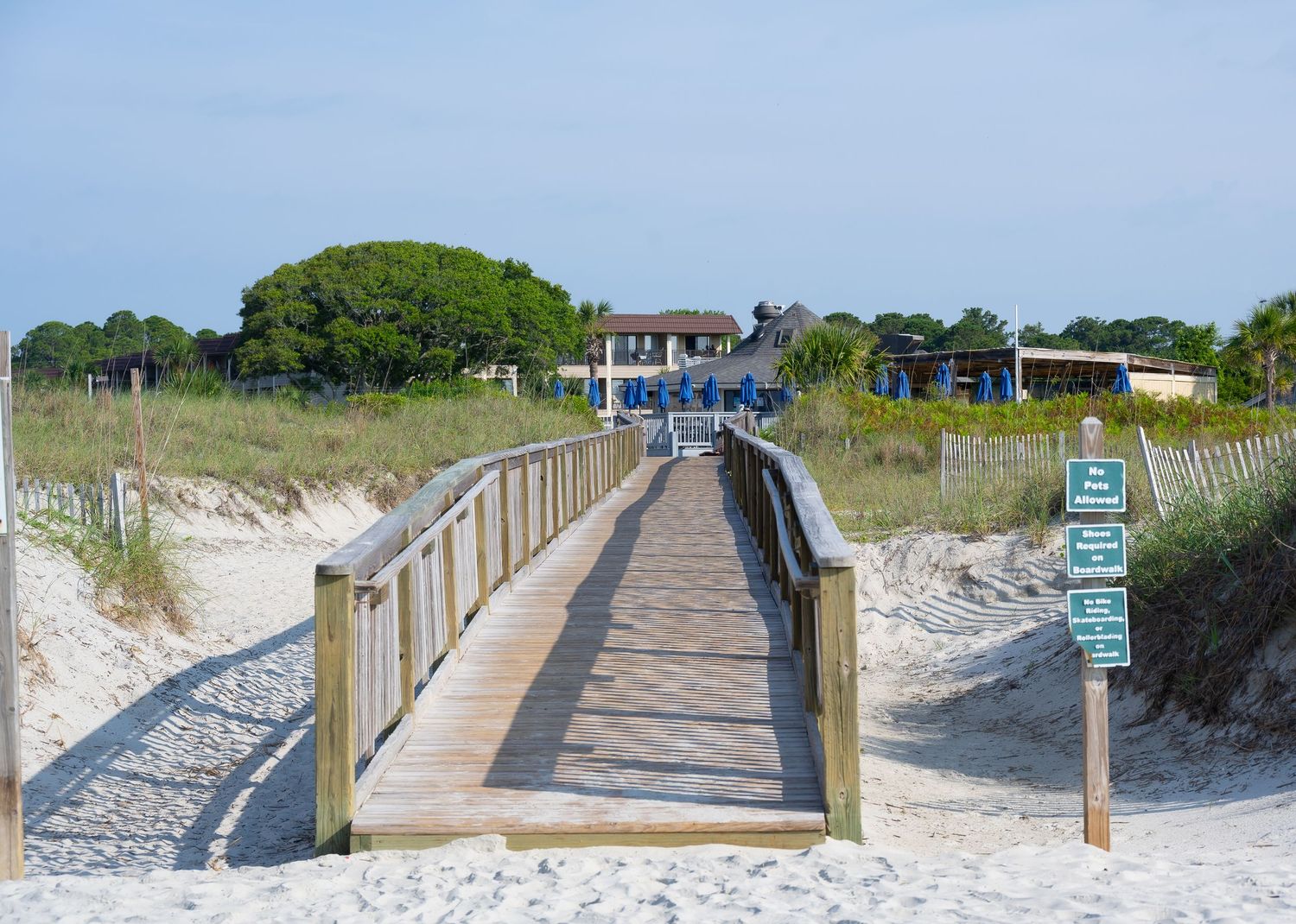 Wooden boardwalk path leads through sand dunes to the beach.