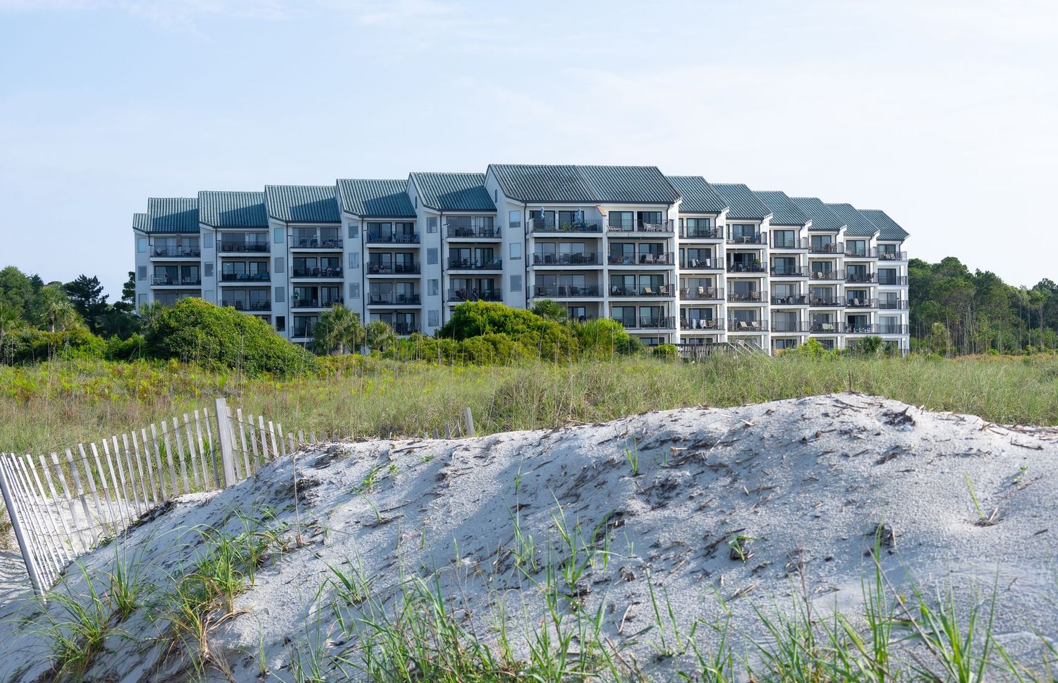 Modern beachfront condominium complex rises above coastal sand dunes.