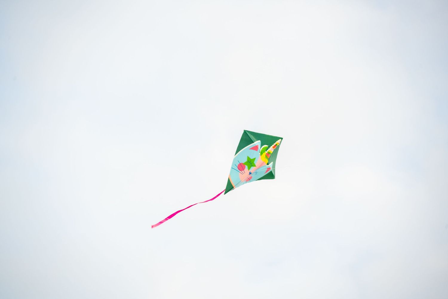 Colorful diamond-shaped kite flying solo in pale blue sky.