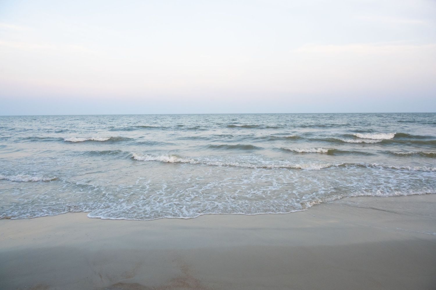 Serene beach landscape with rolling waves meeting the shoreline at dusk.