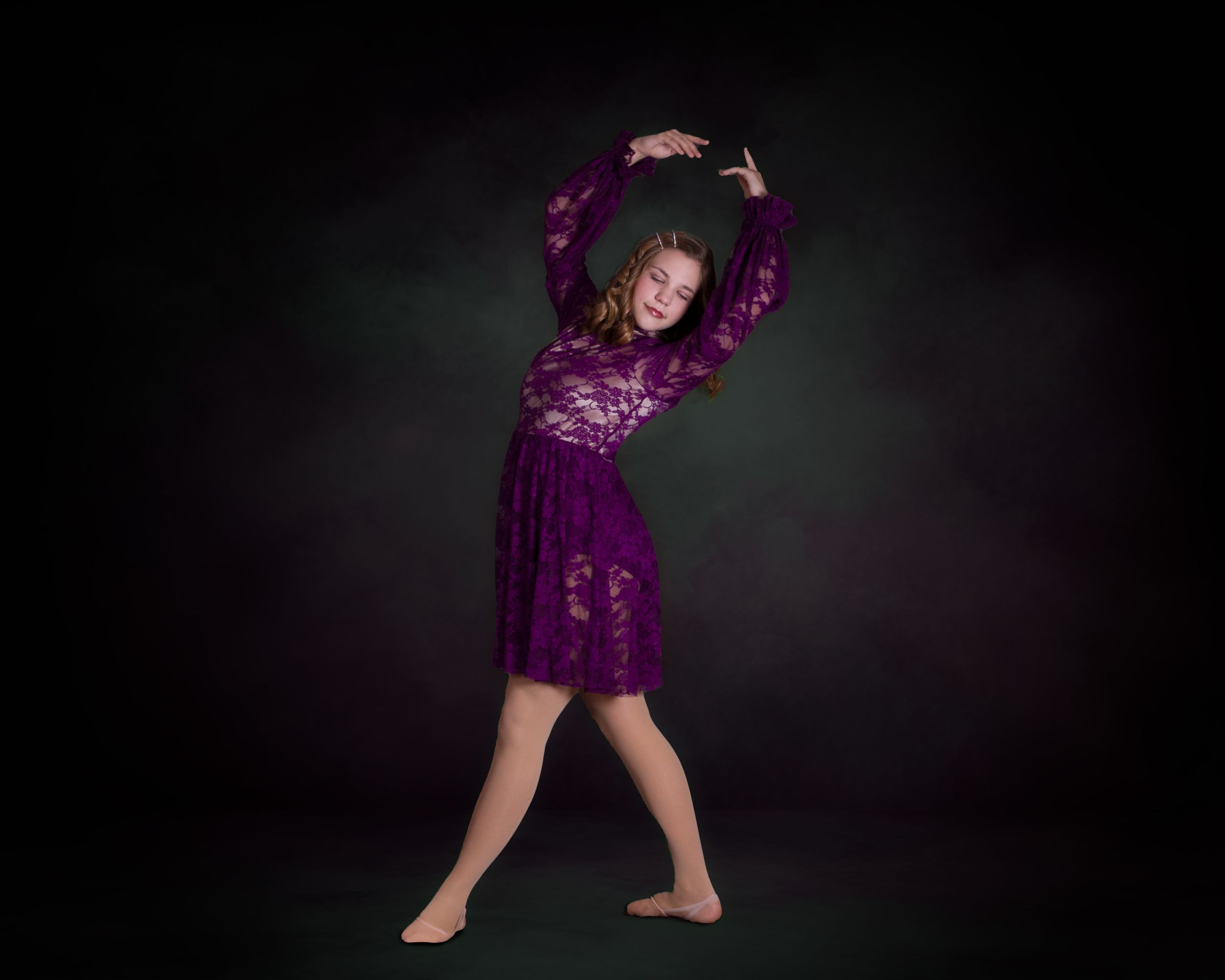 Dancer in purple velvet dress strikes dramatic pose during studio performance.