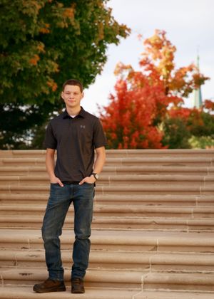 Person standing on concrete steps with autumn trees and foliage in background.