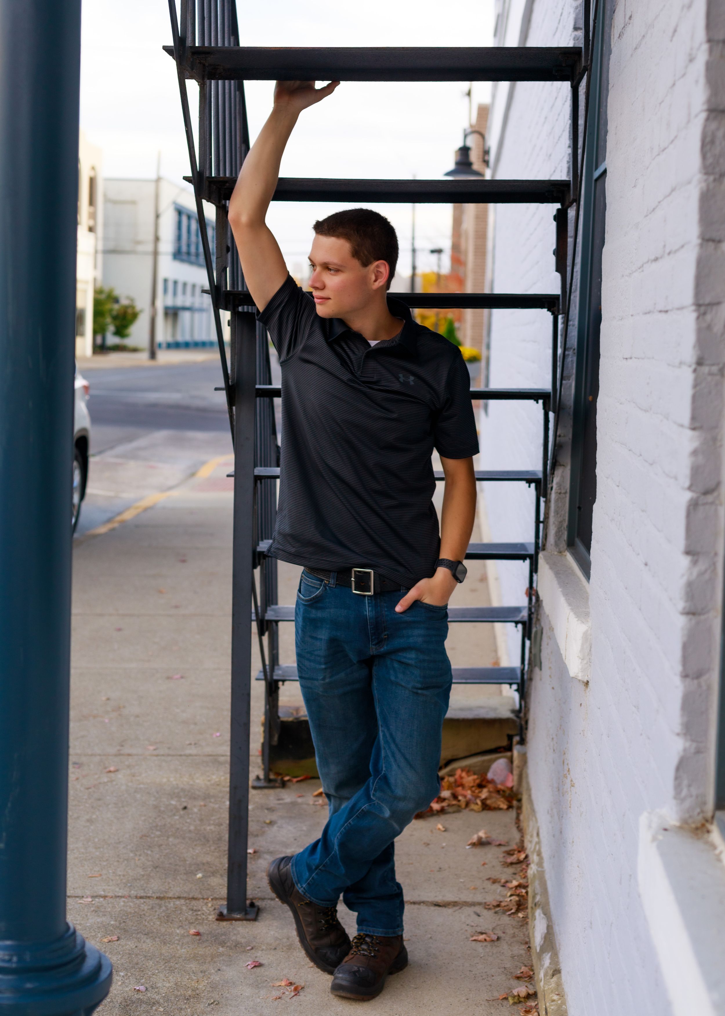 Casual poses along white building exterior with industrial metal columns.