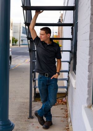 Casual poses along white building exterior with industrial metal columns.