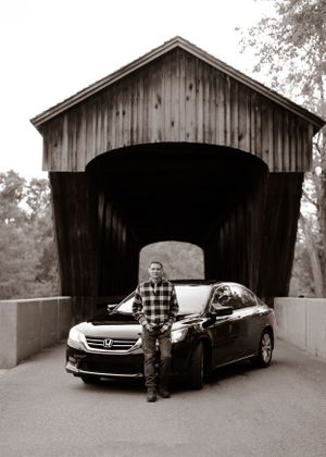 Black and white series showing covered bridge with parked car and person in plaid shirt.