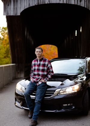 A black Honda sedan parked inside a wooden covered bridge.