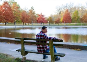 Waterfront park scene with wooden benches and vibrant fall foliage reflecting in calm water.