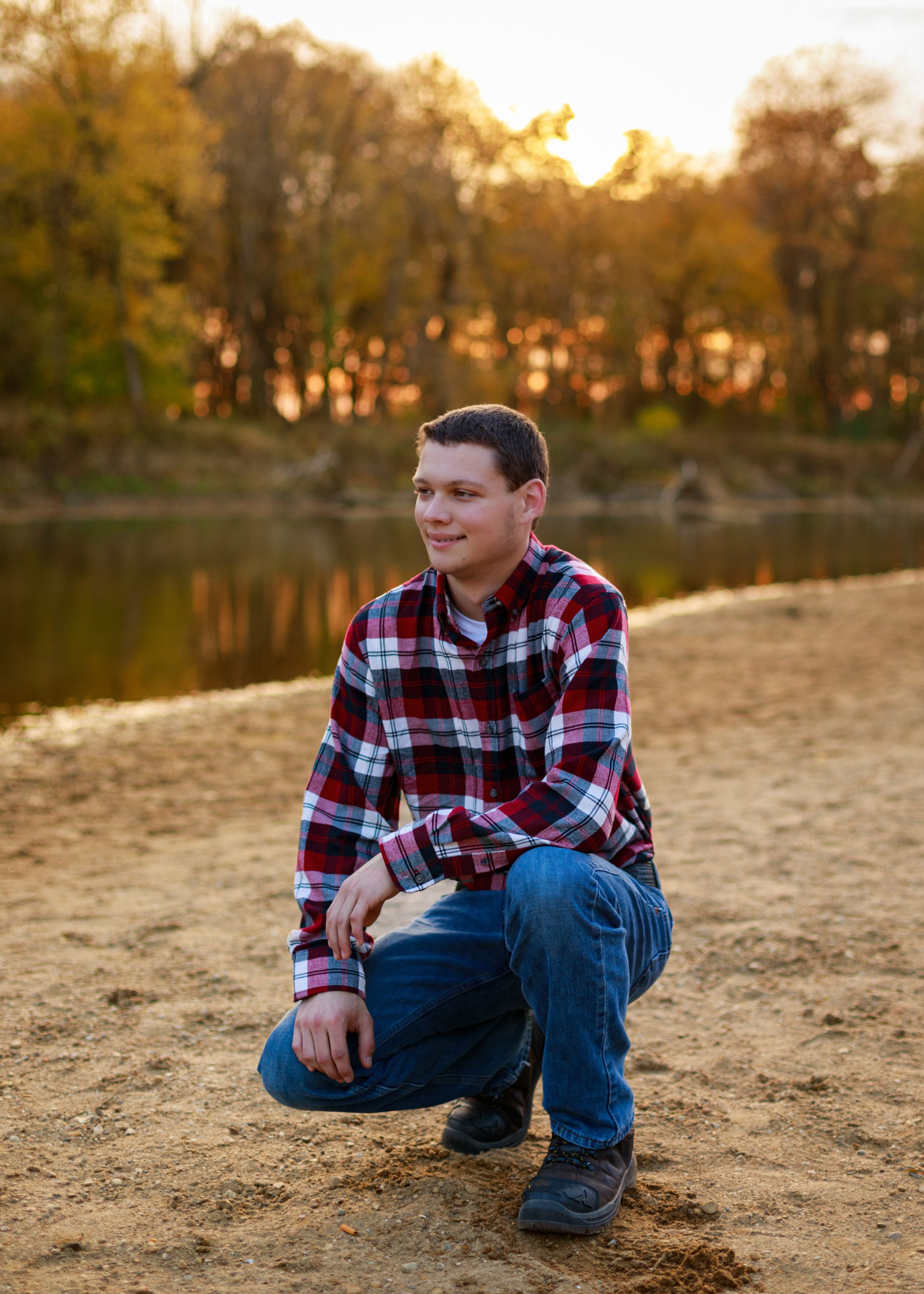 Sunset portrait session on sandy beach with autumn trees in golden light.