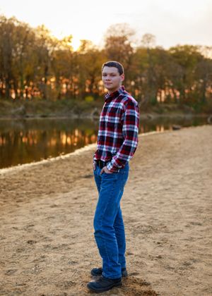 A sandy beach area at sunset with fall foliage and a lake in the background.